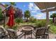 Stone fire pit with seating under a pergola in a landscaped backyard with mature trees at 4326 Spooner Lake Cir, Las Vegas, NV 89147