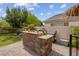 Built-in outdoor grill and bar area with stone surround on a brick patio at 4326 Spooner Lake Cir, Las Vegas, NV 89147