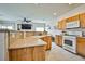 Open kitchen showcasing oak cabinets, white appliances, and a breakfast bar overlooking the living area at 4833 Straight Flush Dr # 103, Las Vegas, NV 89122