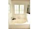 Bright bathroom featuring a soaking tub with shuttered window and decorative tile accent at 5104 Burr Oak Dr, Las Vegas, NV 89130