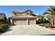 Two-story home with a three-car garage, desert landscaping, and a spacious driveway at 5104 Burr Oak Dr, Las Vegas, NV 89130
