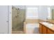 Bright bathroom featuring a soaking tub with tile surround and a vanity with neutral-toned granite countertop at 610 Playa Del Sol Way, Henderson, NV 89015