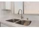 Close-up of stainless steel sink with designer faucet, white cabinets, and stone countertops at 6140 Passionate Ct, North Las Vegas, NV 89031