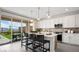Modern kitchen island with chairs, quartz countertops, and sliding glass door to the patio at 64 Via Montoro, Henderson, NV 89011