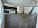 Open-concept living room with gray wood-look tile flooring, kitchen island, and staircase at 64 Via Montoro, Henderson, NV 89011