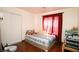 Bedroom with wood floors, closet with sliding doors, and a window with red curtains at 6520 Blooming Sun Ct, Las Vegas, NV 89142