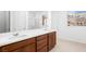 Bright bathroom with double sinks, wood cabinets, white quartz countertops, and a view of the surrounding landscape at 72 Via Montoro, Henderson, NV 89011