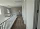 Upstairs hallway with neutral carpet, white walls and banister, and access to multiple rooms at 72 Via Montoro, Henderson, NV 89011