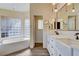 Bright bathroom featuring a double vanity, modern lighting, soaking tub, and stylish faucets at 7417 Radville Dr, Las Vegas, NV 89129