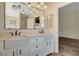 Well-lit bathroom featuring a double vanity, a soaking tub, and modern lighting fixtures at 7417 Radville Dr, Las Vegas, NV 89129