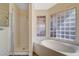 Bright bathroom with a glass block window, soaking tub, and a separate shower at 7417 Radville Dr, Las Vegas, NV 89129