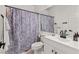 Bright bathroom featuring a large mirror, white vanity with black hardware, and shower with a floral-patterned curtain at 10180 Delray Beach Ave # 202, Las Vegas, NV 89129