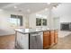 Kitchen island with sink, oak cabinets, and stainless steel dishwasher overlooking the living room at 11569 Velicata Ct, Las Vegas, NV 89138