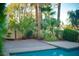 Serene backyard featuring a shimmering pool, lush palm trees, and ample patio space for outdoor enjoyment at 2104 Inverness Dr, Henderson, NV 89074