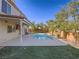 Backyard features an inground pool, artificial grass, patio, and mature trees offering shade at 2732 Dune Cove Rd, Las Vegas, NV 89117