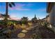 Beautiful backyard with desert landscaping, stone pathway, and inviting patio with outdoor dining area at twilight at 2749 Liberation Dr, Henderson, NV 89044
