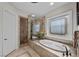 Luxurious bathroom featuring a soaking tub, glass enclosed shower, and decorative window at 2749 Liberation Dr, Henderson, NV 89044