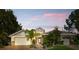 Inviting home with a three-car garage, landscaped front yard, and sunset-painted skies above at 3000 Hammerwood Dr, Las Vegas, NV 89135
