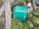Aerial view showcases the vibrant green roof surrounded by lush trees and the adjacent quiet road at 401 Alpine Way, Las Vegas, NV 89124