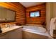 Bathroom featuring a jacuzzi tub with marble surround, accented by a framed mirror and wood paneled walls at 401 Alpine Way, Las Vegas, NV 89124