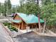 Charming log cabin with a green metal roof nestled among the trees in a mountain setting at 401 Alpine Way, Las Vegas, NV 89124