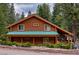 Charming log cabin with a vibrant green roof, nestled among lush trees and manicured greenery at 401 Alpine Way, Las Vegas, NV 89124