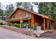 Charming log cabin with a green roof, lush landscaping, and stone retaining wall on a sloped lot at 401 Alpine Way, Las Vegas, NV 89124