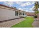 Side view of backyard showcasing brick patio, hardscape and synthetic grass at 4176 Demoline Cir, Las Vegas, NV 89141