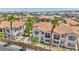 Beautiful two-story condo with light blue window shutters, lush landscaping, and a red tile roof, surrounded by palm trees at 50 Aura De Blanco St # 2104, Henderson, NV 89074