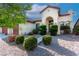 Front exterior of home featuring stucco siding, three-car garage, arched entry, and manicured landscaping at 5016 Wayfaring Tree Ave, Las Vegas, NV 89131