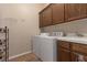 A laundry room with upper cabinets, sink, washer, and dryer with neutral walls and tile floor at 5016 Wayfaring Tree Ave, Las Vegas, NV 89131