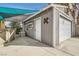 A gray garage has a full and partial garage door, a side door and a patio area with a partial shade covering at 5217 Champions Ave, Las Vegas, NV 89142
