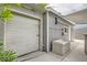 A gray garage has a full metal roll up door with an attached patio area, with a partial shade covering at 5217 Champions Ave, Las Vegas, NV 89142