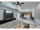 Open-concept living room flowing into the kitchen with a large TV, a ceiling fan, and sliding glass doors at 6052 Puesta Del Sol St, North Las Vegas, NV 89081