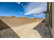 View of an empty backyard with a block wall fence under a bright blue sky with fair weather clouds at 6607 Summershade St, North Las Vegas, NV 89086