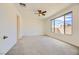Spacious bedroom with carpeted floors, ceiling fan, large window, and access to the rest of the home at 6607 Summershade St, North Las Vegas, NV 89086