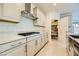 Well-equipped kitchen with stainless steel vent hood, gas cooktop, pantry access, and modern countertops at 6607 Summershade St, North Las Vegas, NV 89086
