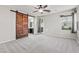 Spacious bedroom with a ceiling fan, ensuite bath, and sliding barn door at 8220 Chimney Bluffs St, North Las Vegas, NV 89085