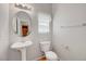 Bathroom with a pedestal sink, round mirror and natural light at 1574 Ward Frontier Ln, Henderson, NV 89002