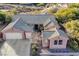 Aerial view of a pink stucco home with a tile roof, three-car garage, and desert landscaping at 2039 Colvin Run Dr, Henderson, NV 89052