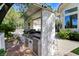 Outdoor kitchen with built-in grill and bar area amid tropical landscaping at 2345 Villandry Ct, Henderson, NV 89074