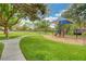 Community playground with a shaded play structure, swing set, and picnic tables amid mature trees and a grassy area at 2345 Villandry Ct, Henderson, NV 89074