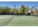 Well-maintained tennis court with pristine green surface surrounded by mature trees at 2345 Villandry Ct, Henderson, NV 89074