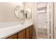 Bathroom with wood cabinets, bright counter, round mirror and tub/shower combo at 2521 Cattrack Ave, North Las Vegas, NV 89081