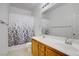 Well-lit bathroom featuring double sinks with wood cabinets and a shower/tub with black and white curtains at 2851 Glistening Grove Ave, Henderson, NV 89052