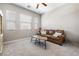 Cozy living room with plush carpet, three windows, and a comfortable leather couch at 417 Honeybrush Ave, Henderson, NV 89011