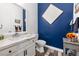 Stylish powder room featuring blue walls, a marble-look counter, and wood-look flooring at 417 Honeybrush Ave, Henderson, NV 89011