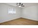 A minimalist bedroom with light wood flooring, a ceiling fan, and a window letting in natural light at 4797 E Imperial Ave, Las Vegas, NV 89104