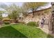 Grassy backyard with terraced garden featuring manicured shrubs, small trees, and decorative rock walls for landscaping at 48 Panorama Crest Ave, Las Vegas, NV 89135