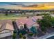 Aerial view of a home with red tile roof and manicured landscaping in golf course community at sunset at 499 Eagle Vista Dr, Henderson, NV 89012